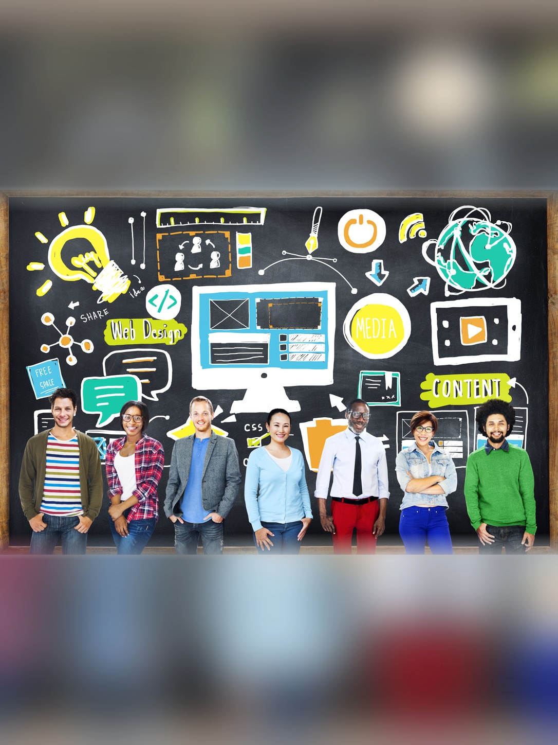 Seven educators stand before a chalkboard filled with web, media, and communication symbols.
