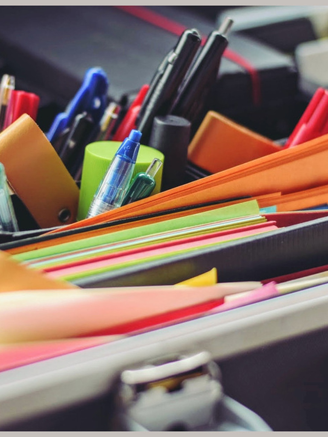 Colorful folders, notebooks, pens, and markers fill an open case.