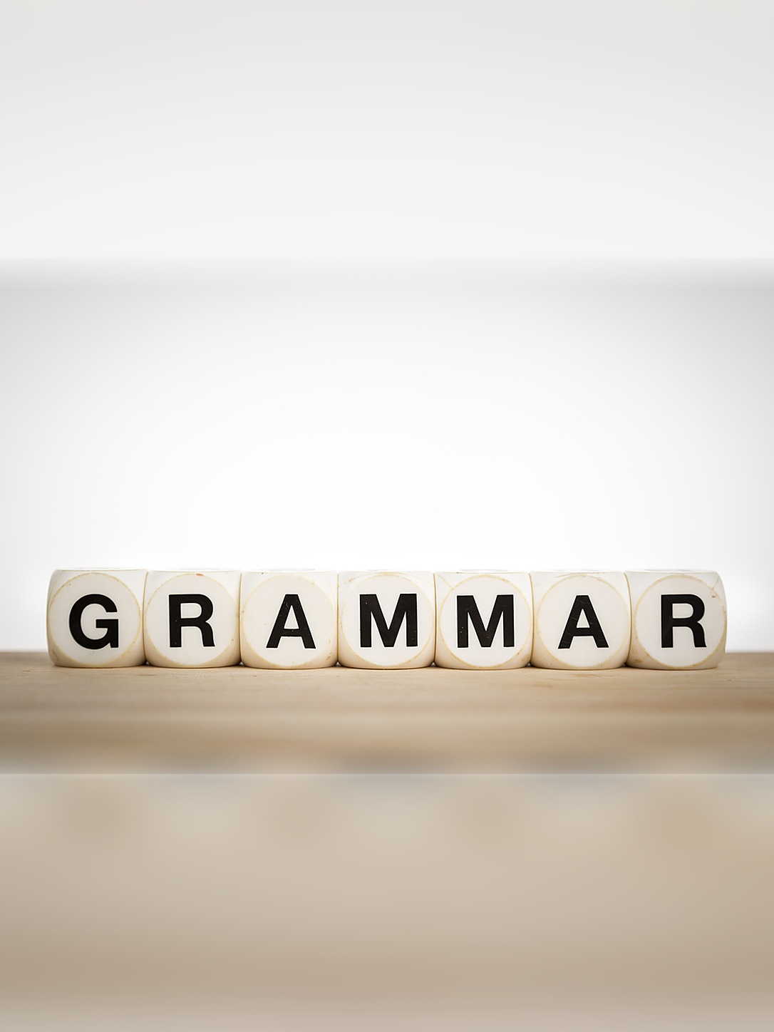 Letter blocks spell “GRAMMAR” on a wooden surface.