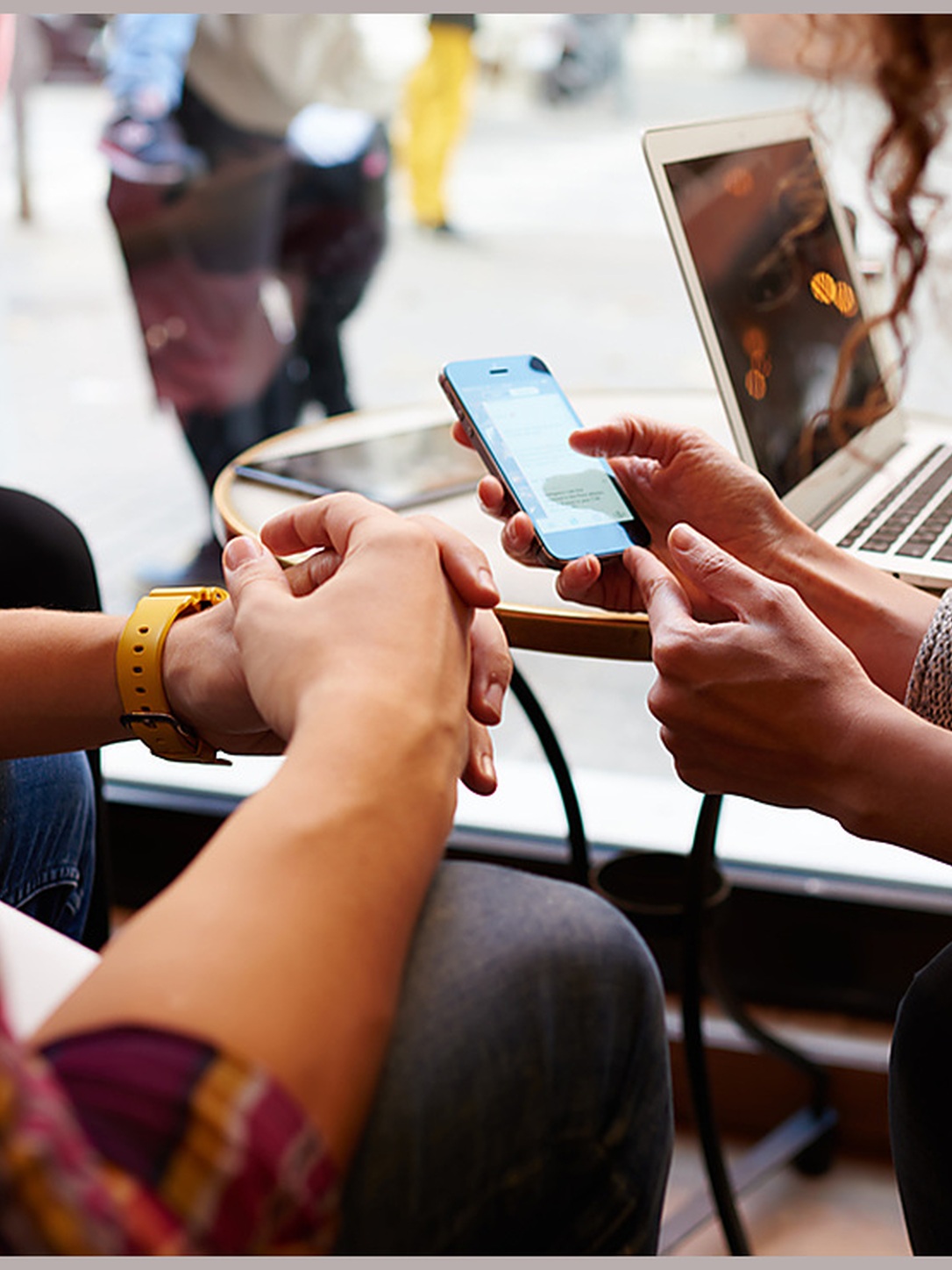 Students use a smartphone and laptop while working together.