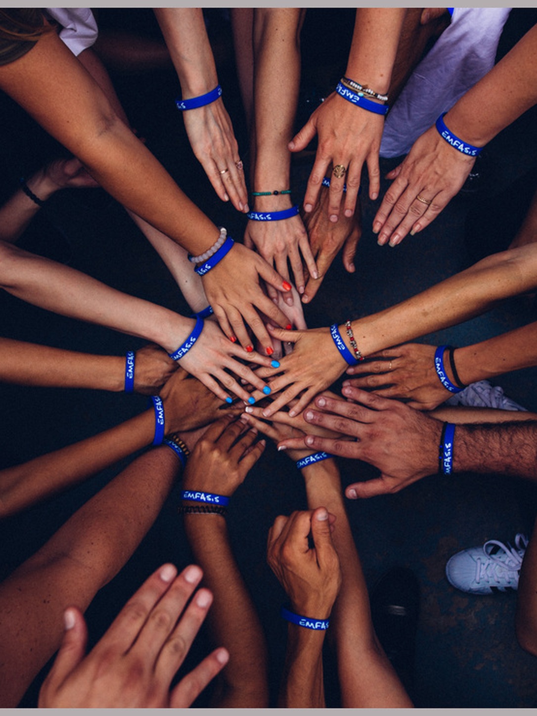 A diverse group places their hands together in a circle.