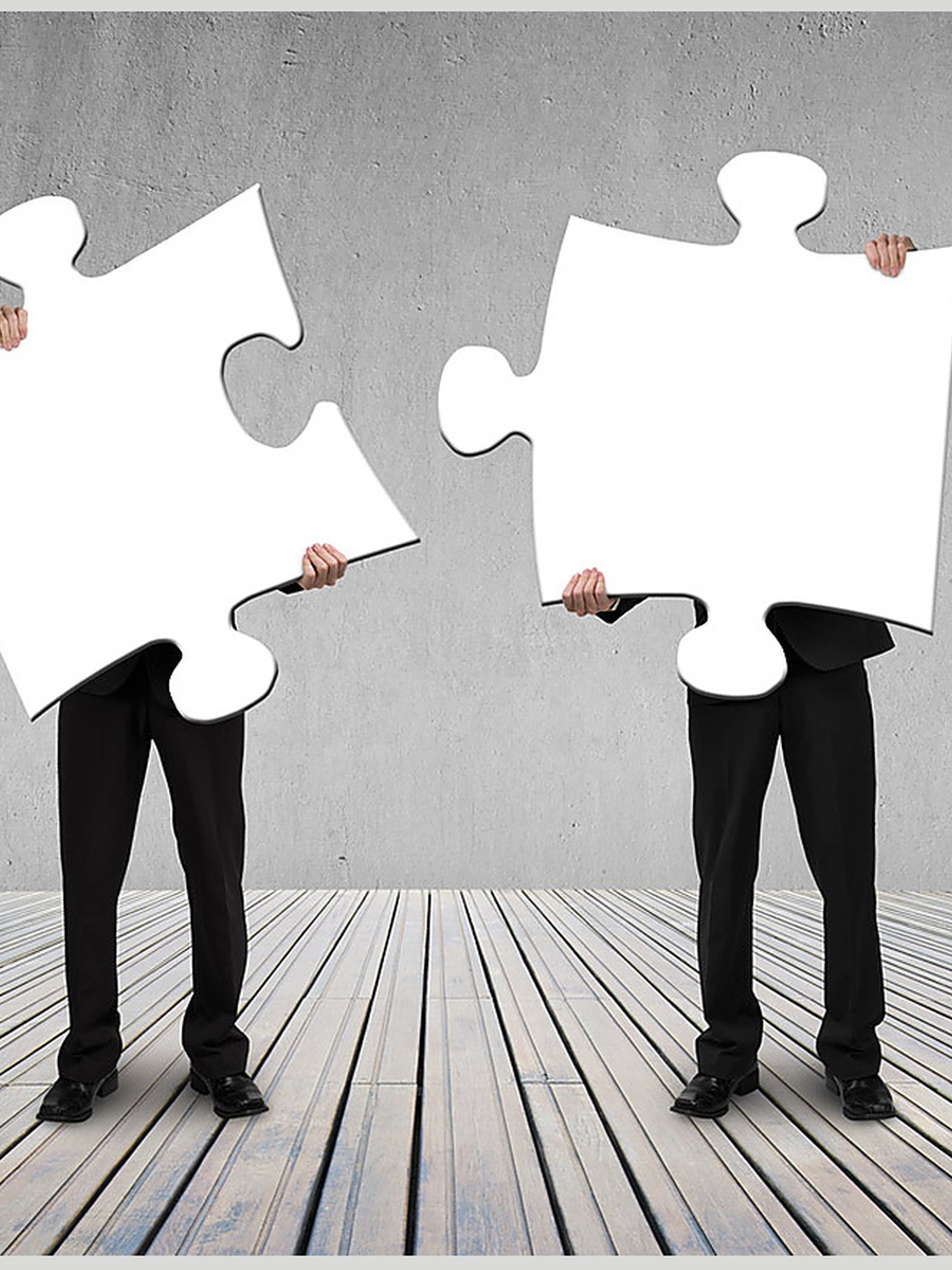 Two people hold large interlocking puzzle pieces.
