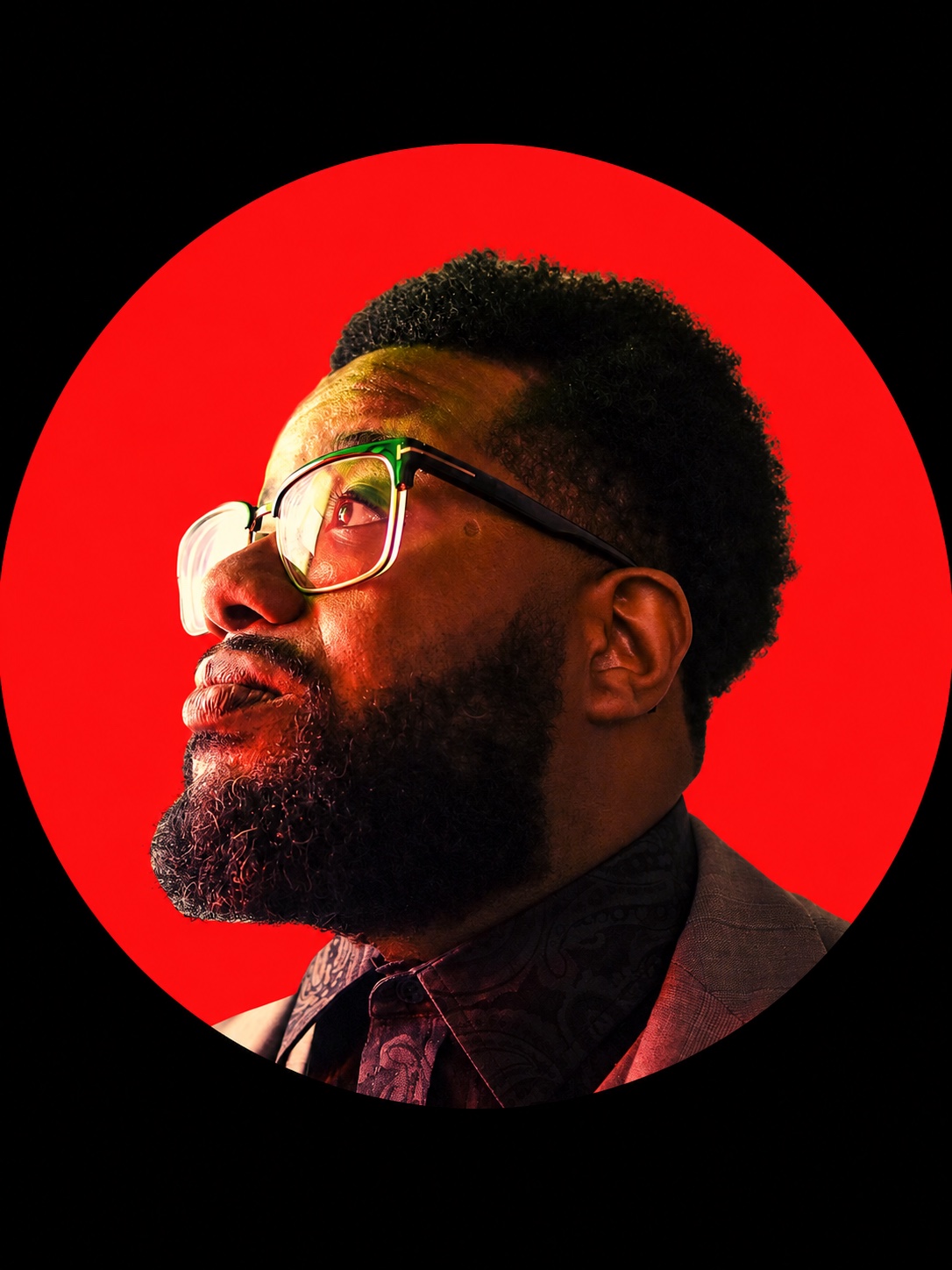Ben Will, wearing glasses, looks upward against a vivid red circle.