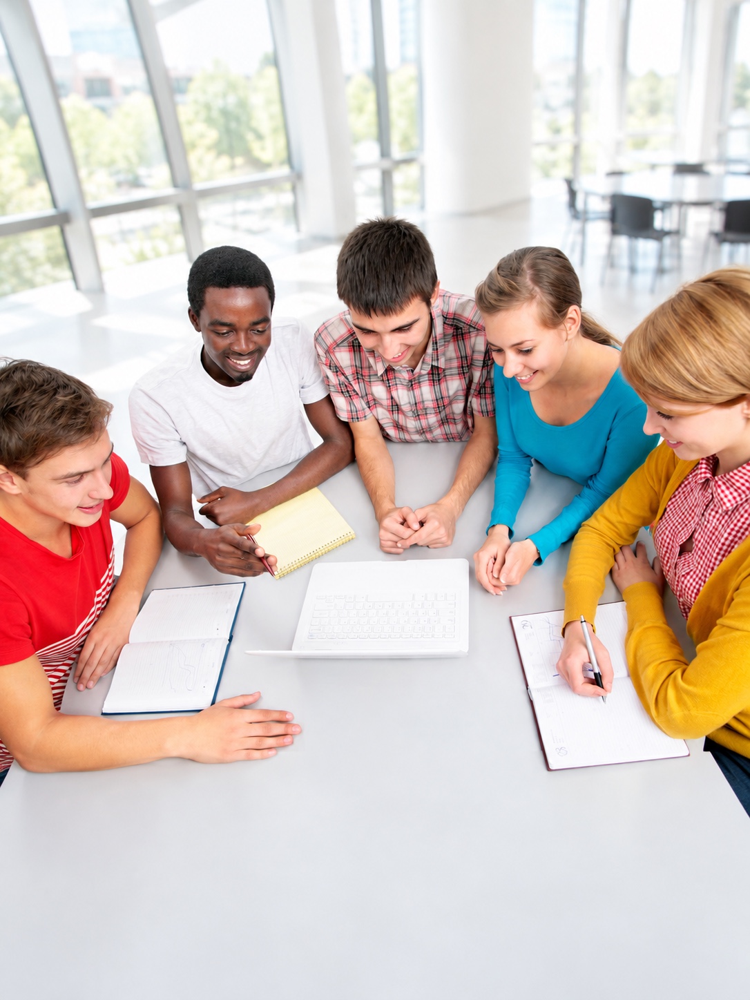 A diverse group of students collaborates around a classroom table.