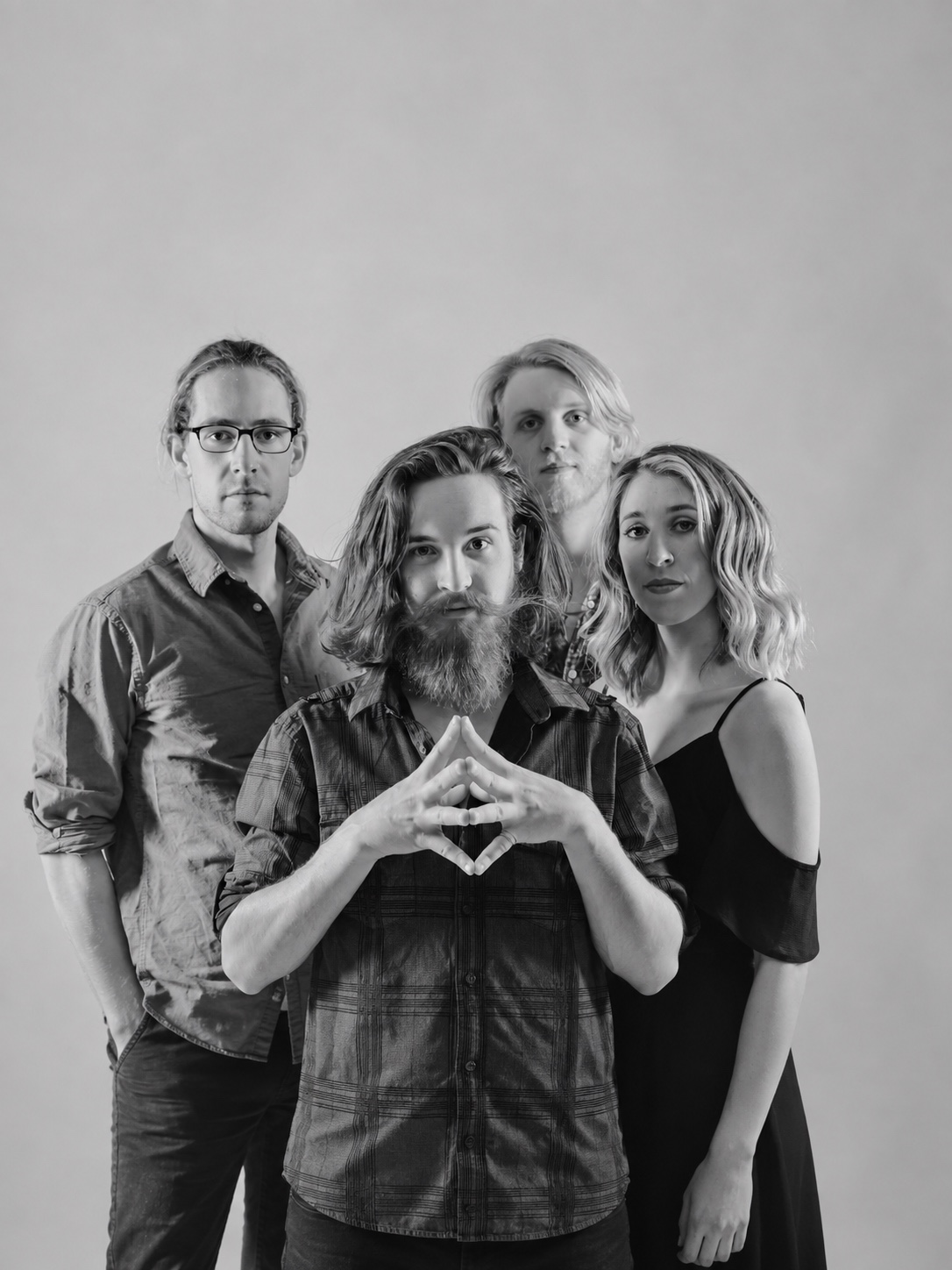 The four members of Damn Tall Buildings pose for a black-and-white portrait.