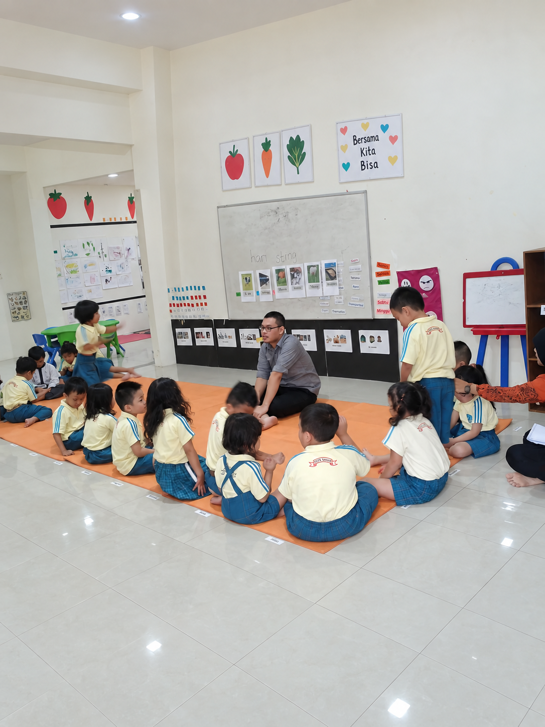 A teacher leads a circle activity with young students in a bright classroom.