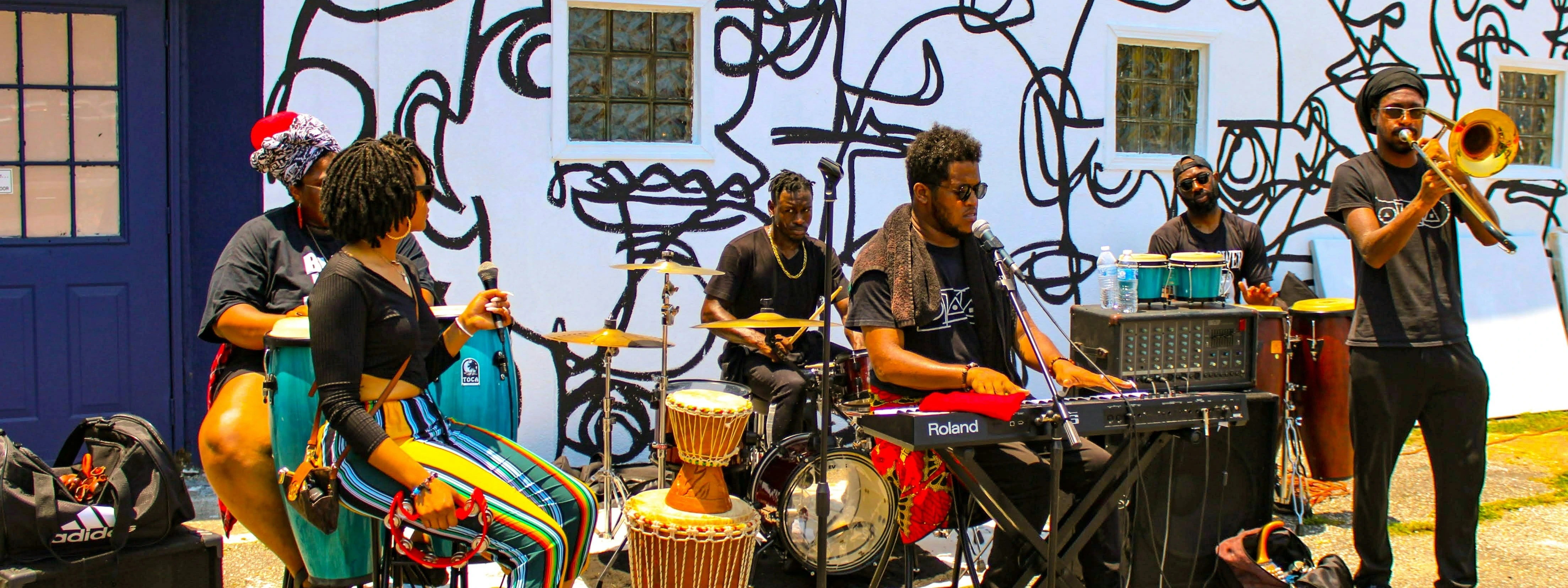 An outdoor band performs with drums and brass instruments.