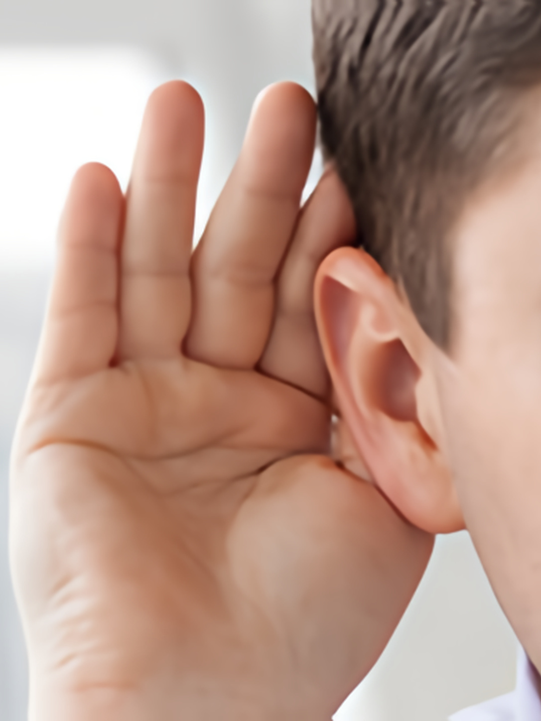A person cups a hand behind an ear to listen closely.