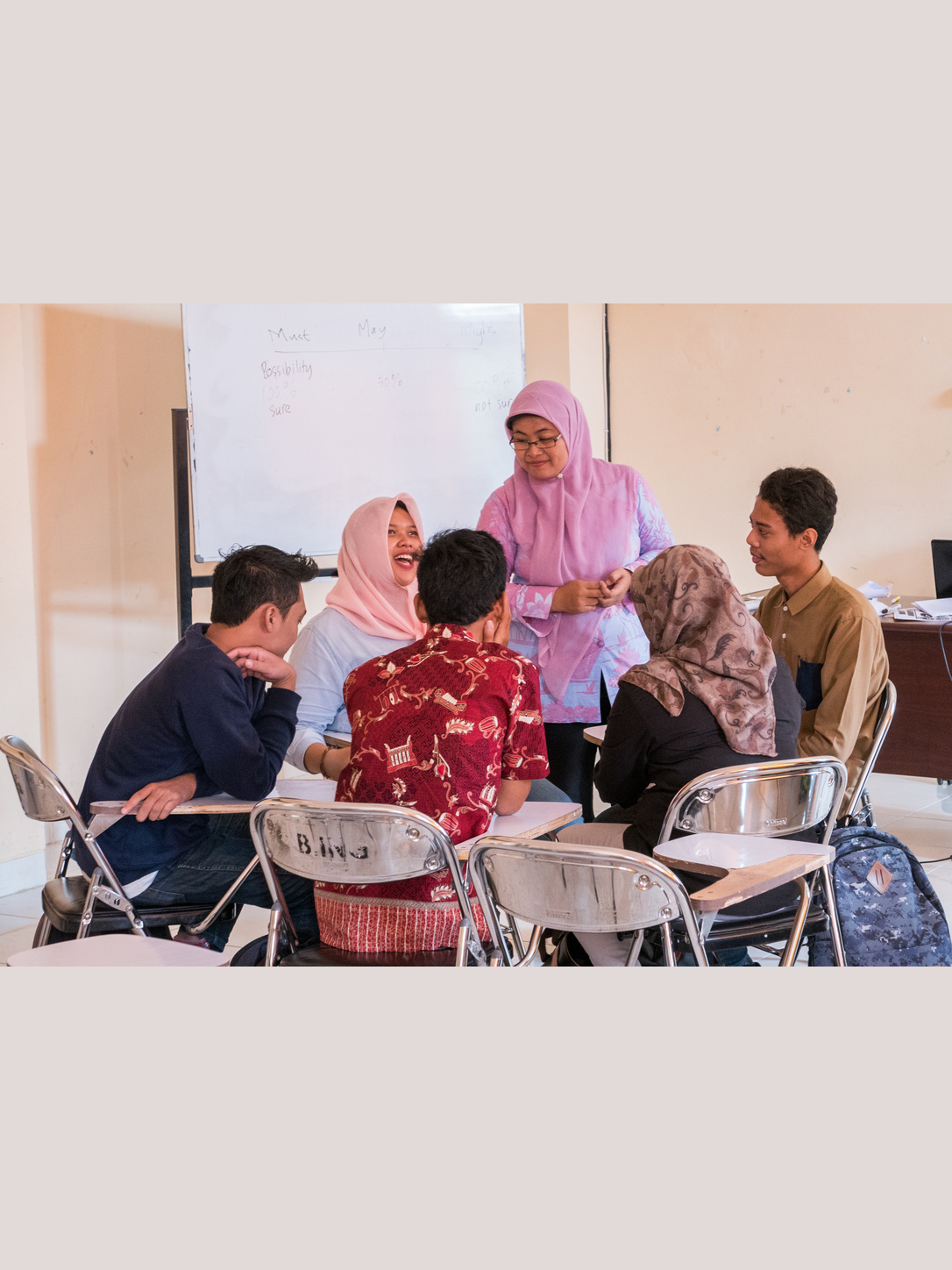 English lecturer Alief Noor Farida stands with five university students seated in a discussion group in a classroom.