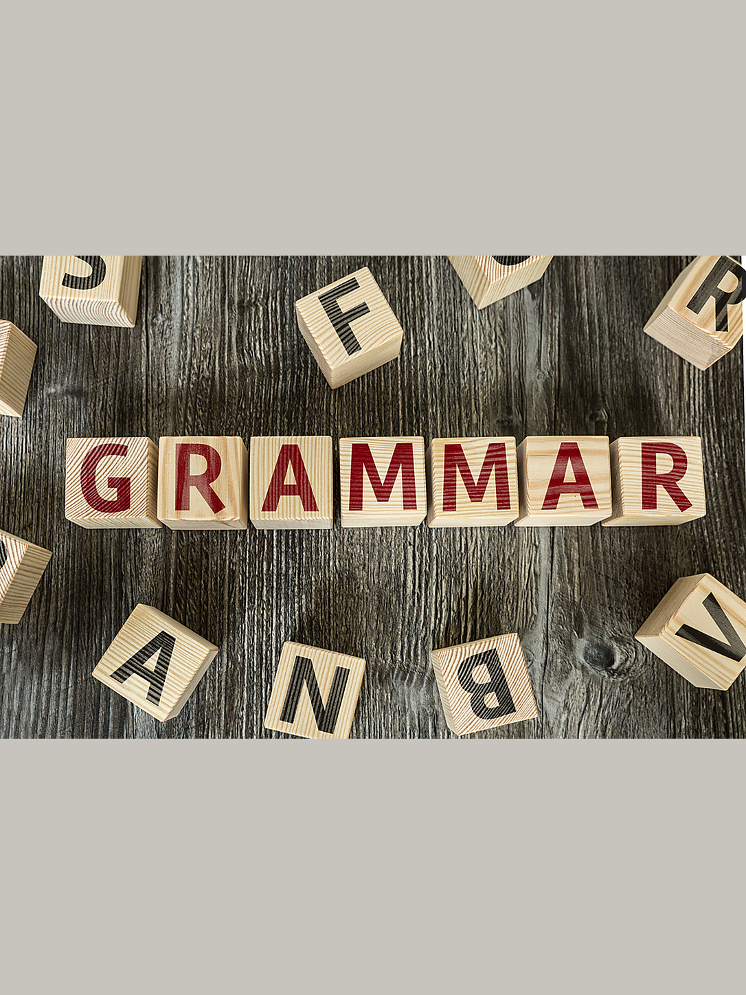 Wooden letter tiles spell “grammar” among scattered alphabet blocks.