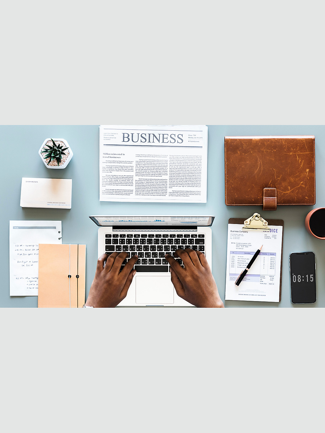 Overhead view of a business workspace with a laptop, business materials, notebook, and phone.