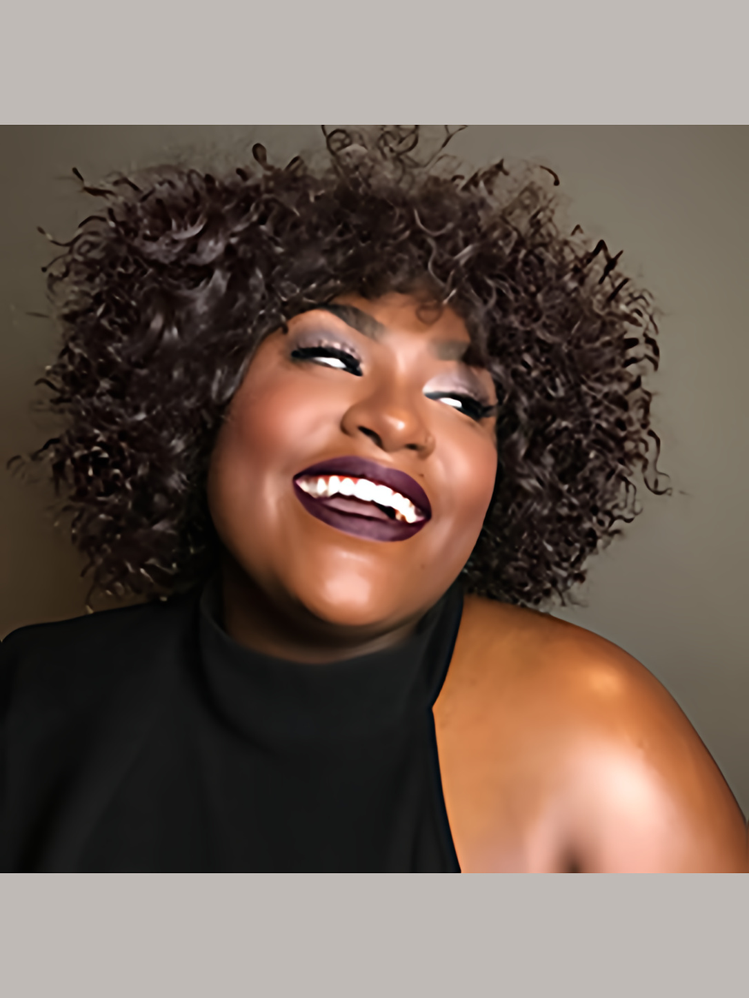 Singer Tamara Jade smiling in a black sleeveless top against a neutral background.